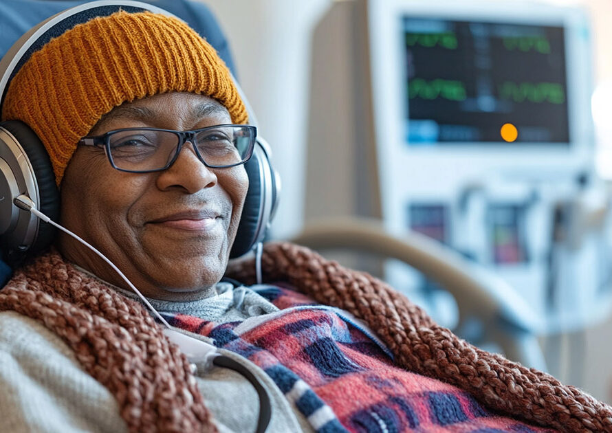 Smiling dialysis patient seated comfortably with a warm blanket and headphones