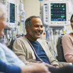 Diverse group of dialysis patients chatting softly in a treatment room, IV machines in background
