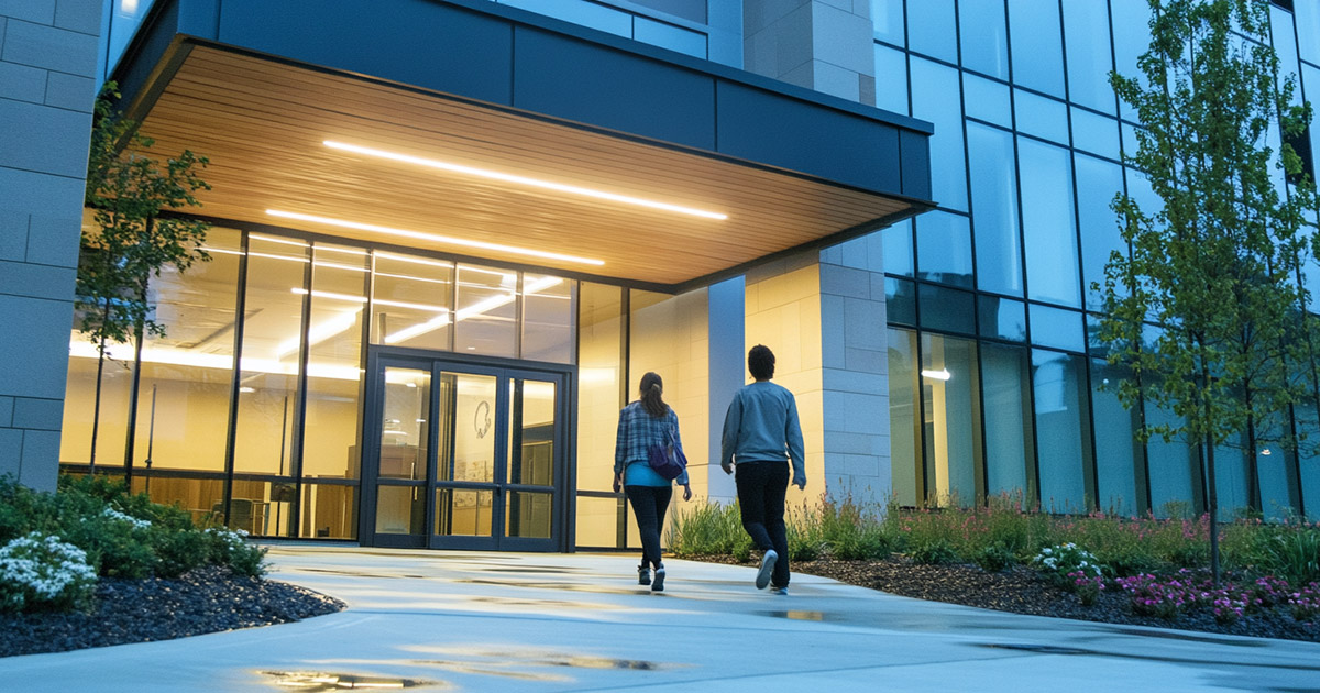 Low-angle shot of two patients walking into a nonprofit health clinic building