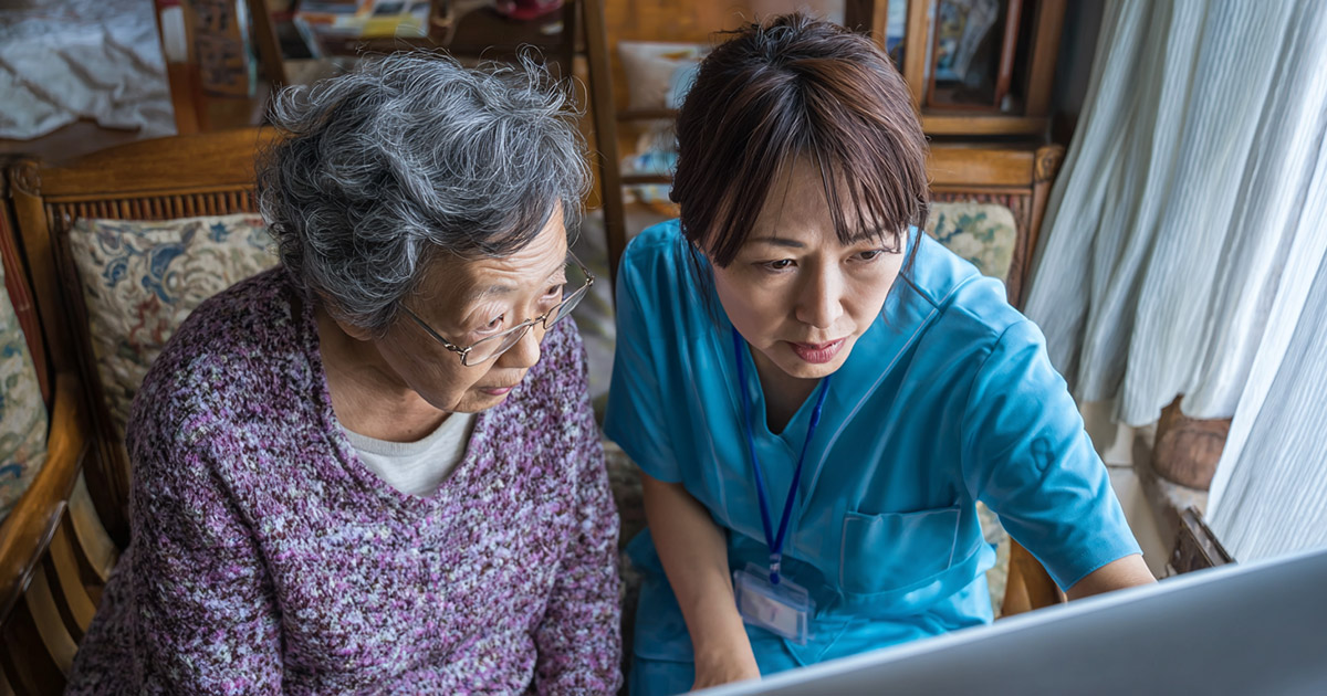 Home healthcare aide assisting elderly patient with funding application