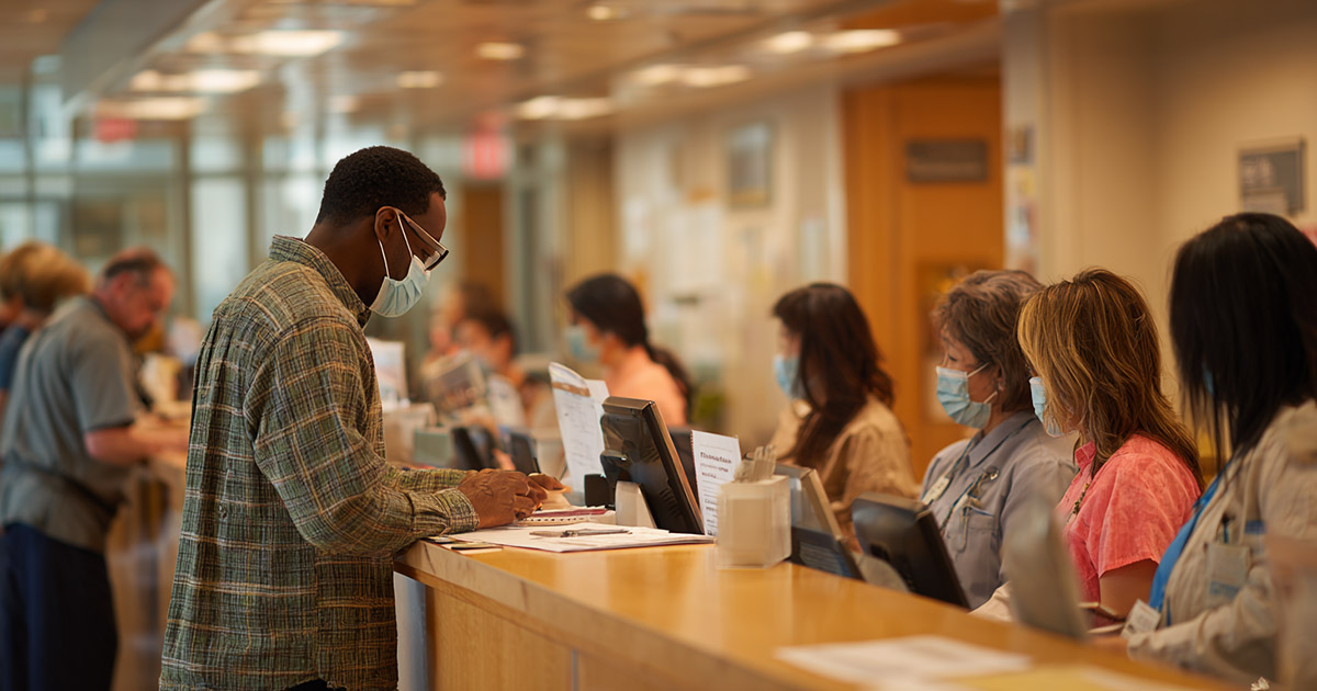 Patient at hospital registration desk affected by medicaid funding cut policies