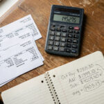 Calculator and pay stubs on a desk for ACA affordability calculations